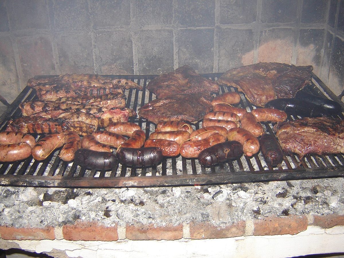 Asado de tira short ribs grilling over embers on a Uruguayan parrilla