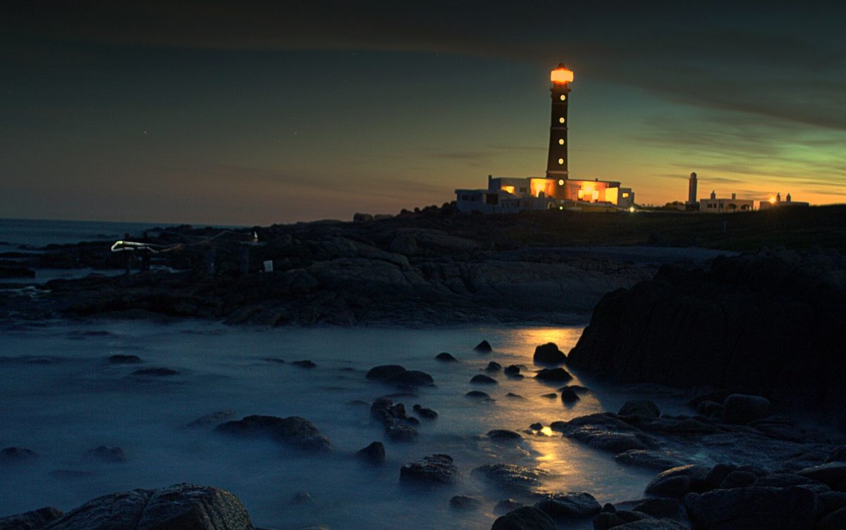 The lighthouse and off-grid houses of Cabo Polonio at dusk above the rocky Atlantic shore