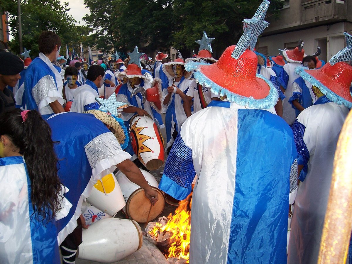 Candombe drummers in costume warming their drums by a fire before the Llamadas parade in Montevideo
