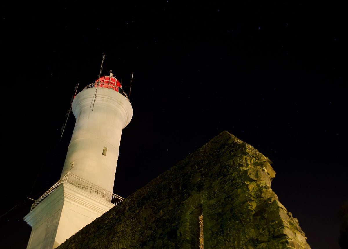 The 1857 lighthouse of Colonia lit at night above the San Francisco convent ruins