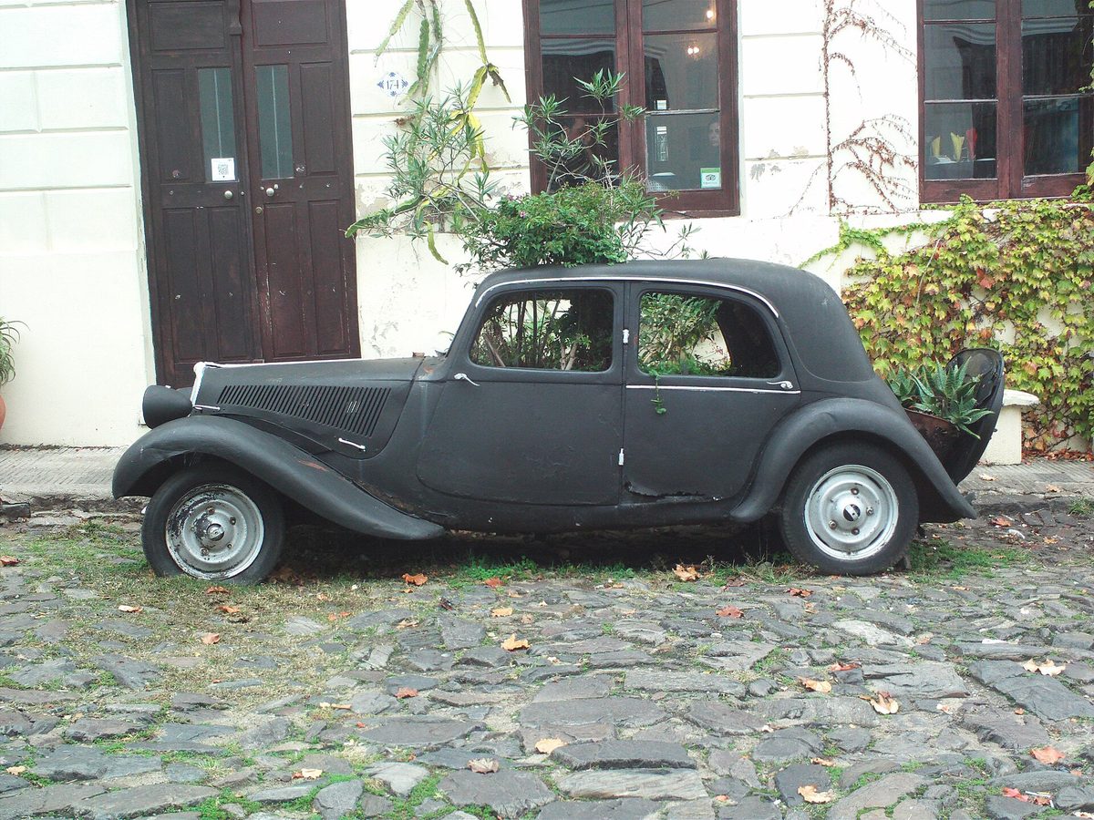 Vintage car with plants growing inside, parked on the cobbles of Colonia's historic quarter