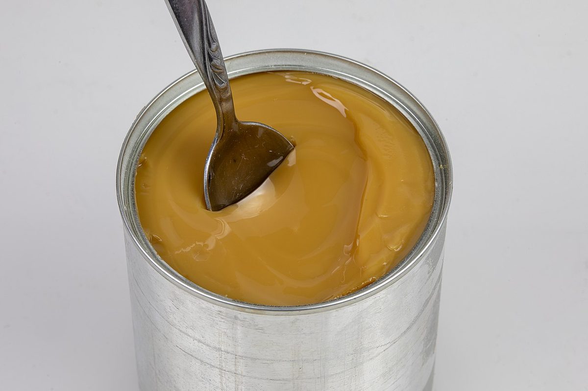 An open tin of dulce de leche with a spoon, the caramelized milk spread used across Uruguay