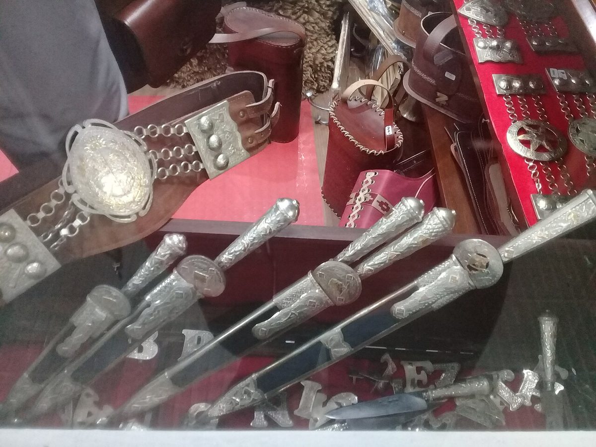 Close-up of a gaucho's facon knife tucked into a silver-coin rastra belt over bombachas