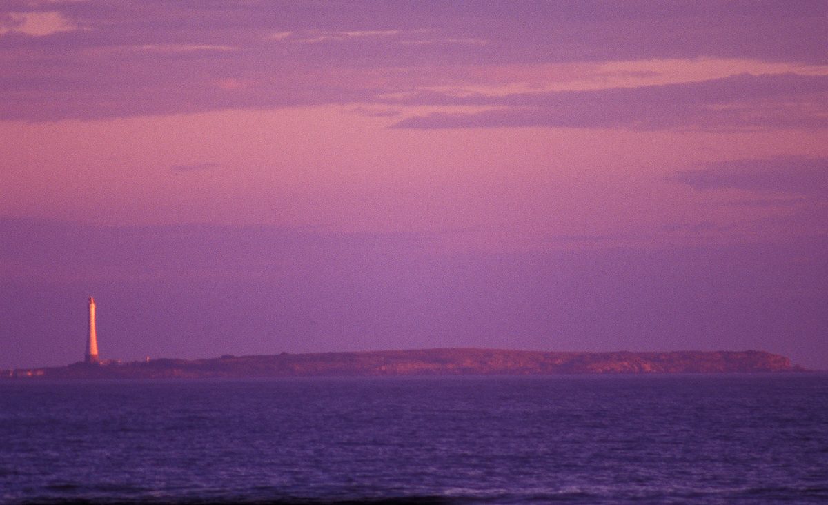 Isla de Lobos and its lighthouse - South America's tallest - glowing at dusk off Punta del Este