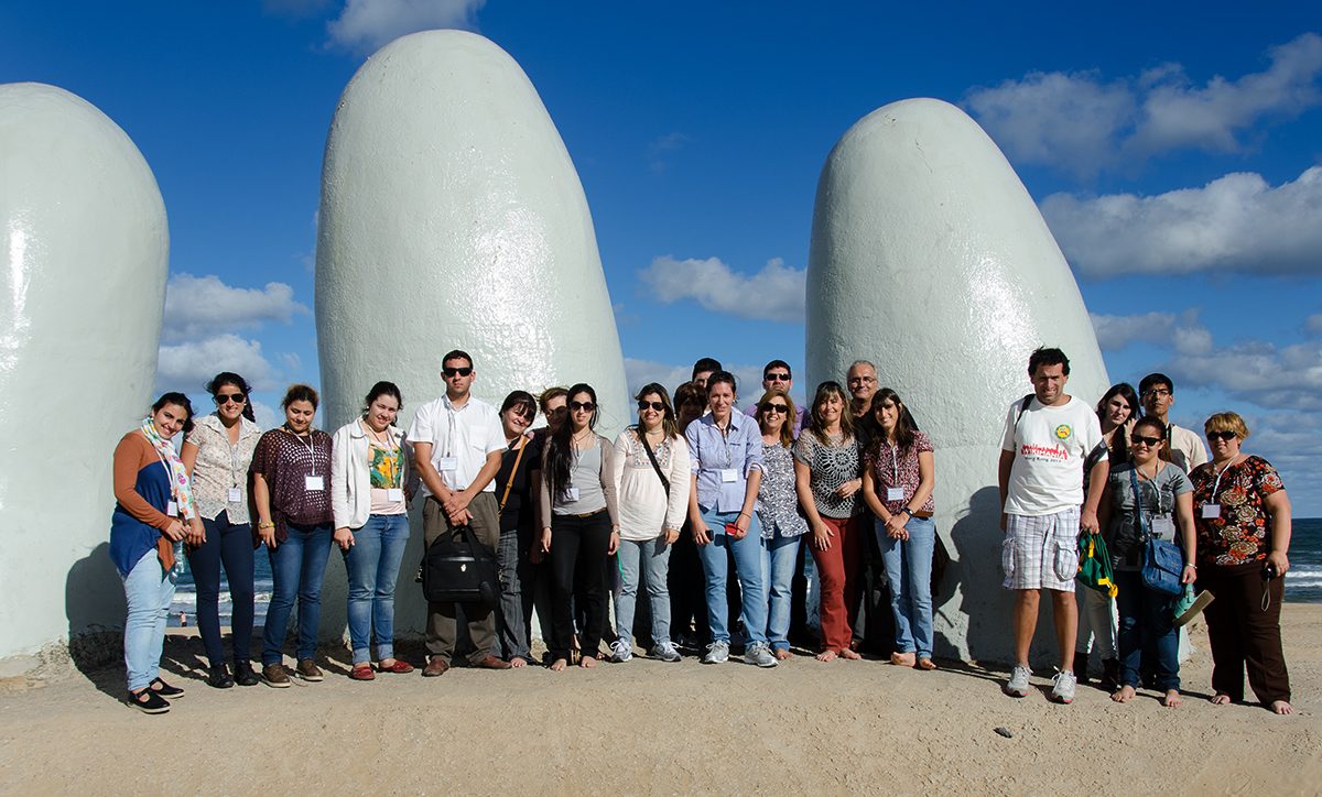 Visitors climbing on the fingers of La Mano, the hand sculpture on Playa Brava