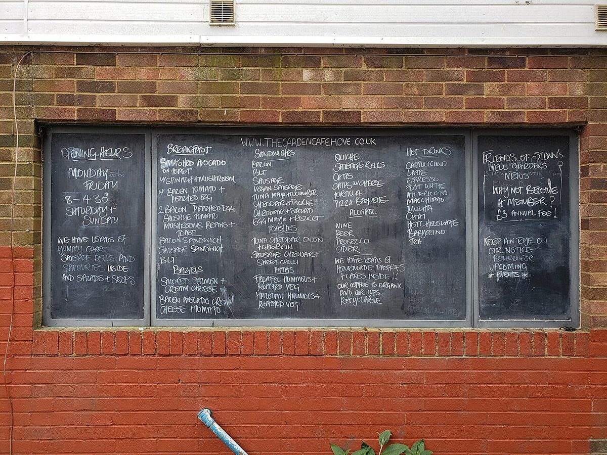 A cafe menu written in Spanish on a chalkboard in Montevideo, listing coffee and pastries