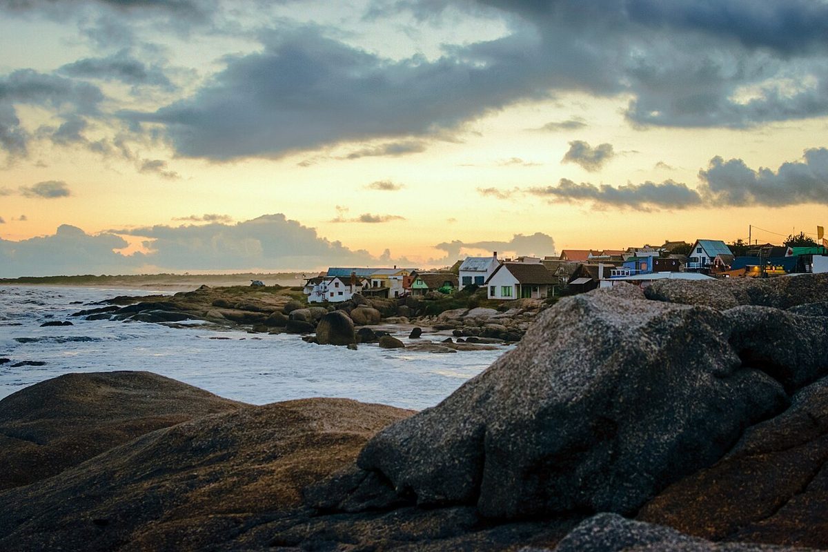 Fishermen's houses above the rocky shore at sunset in Punta del Diablo