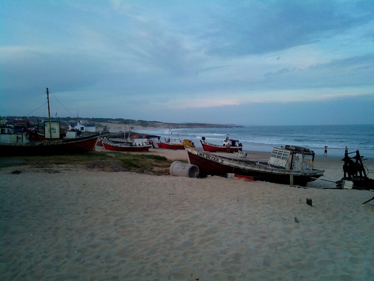 Fishermen and painted boats at the working caleta de pescadores fishing cove in the village