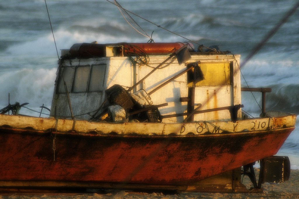 A weathered wooden fishing boat hauled onto the sand at Punta del Diablo